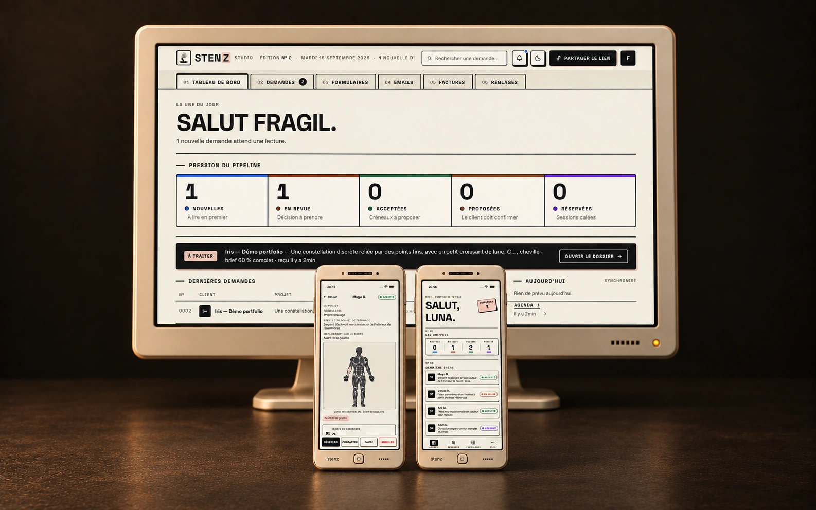 Un grand moniteur rétro crème affichant le dashboard de Stenz Studio, avec deux téléphones au premier plan présentant le brief de tatouage et l’accueil